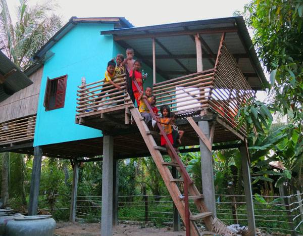 Family sit outside their new Framework House. Photo courtesy of Building Trust International
