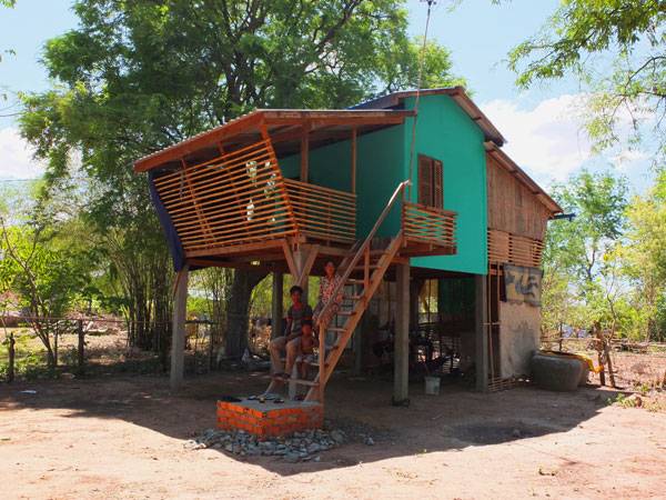 Family sit outside their new Framework House. Photo courtesy of Building Trust International 